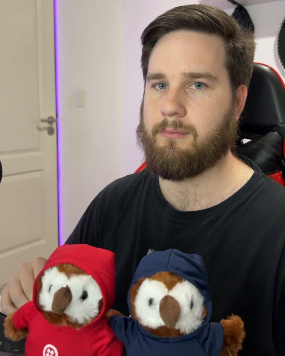 Gonzalo Gomez at his desk, holding two Twilio owl plushies
